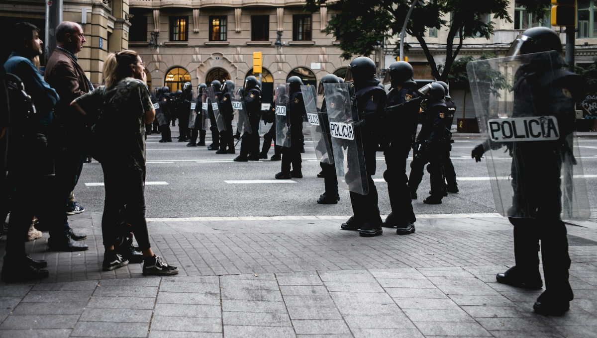 Manifestanti pacifici di fronte alla polizia schierata e armata, una rappresentazione di assimmetria del potere.